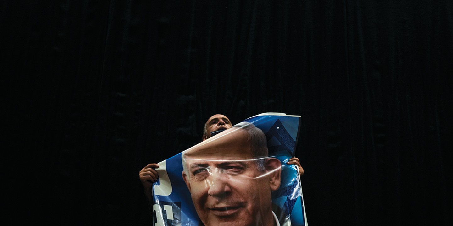 a figure holding a poster of Benjamin Netanyahu